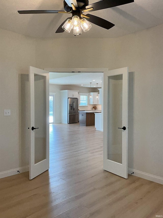 unfurnished room featuring french doors, ceiling fan, and light hardwood / wood-style flooring