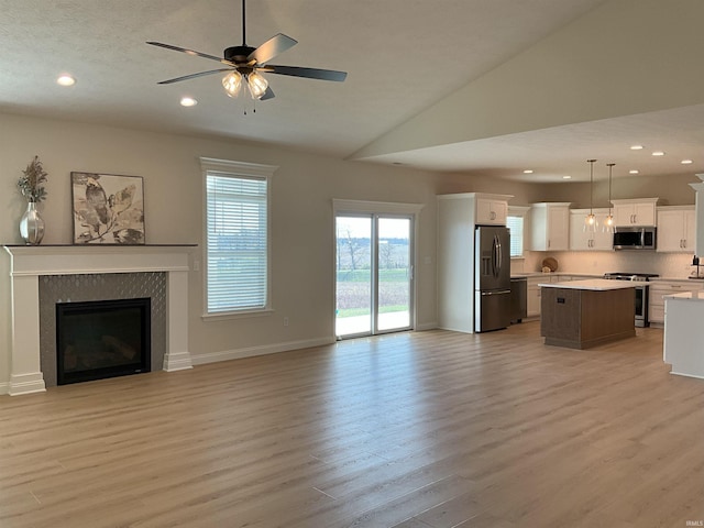 unfurnished living room featuring light hardwood / wood-style floors, ceiling fan, and high vaulted ceiling