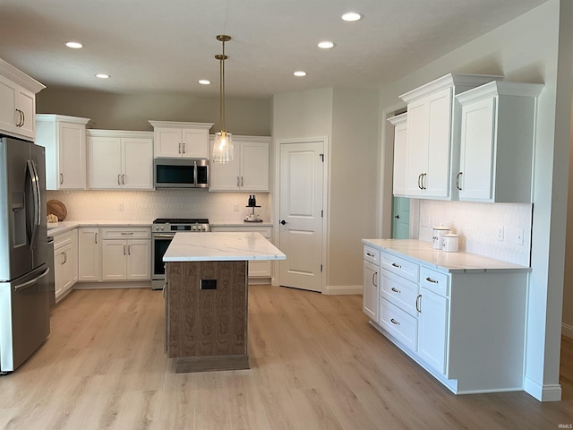 kitchen with stainless steel appliances, pendant lighting, a kitchen island, and light wood-type flooring