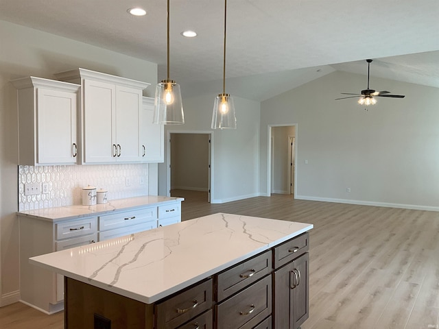 kitchen featuring white cabinetry, tasteful backsplash, light hardwood / wood-style flooring, pendant lighting, and vaulted ceiling