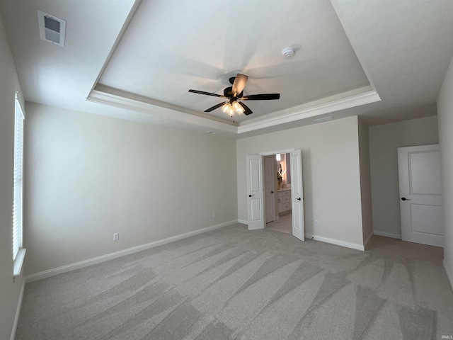 unfurnished bedroom featuring ornamental molding, light colored carpet, ceiling fan, and a raised ceiling