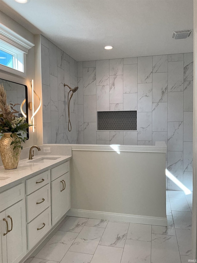 bathroom with vanity and a tile shower