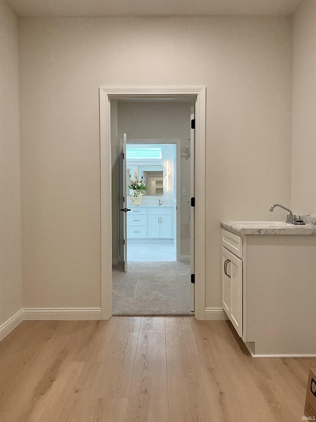 corridor with light hardwood / wood-style floors and sink