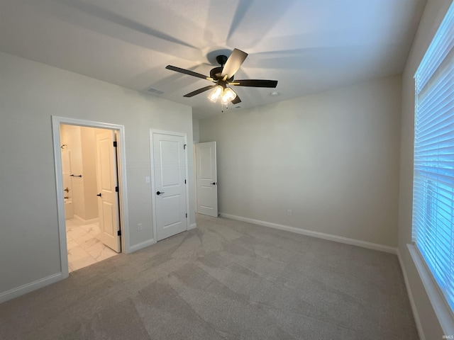 unfurnished bedroom featuring light colored carpet, ceiling fan, and ensuite bath