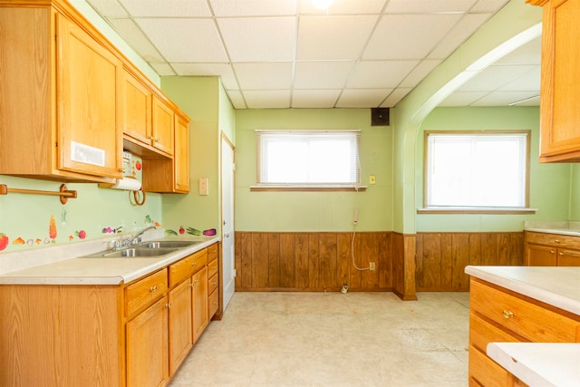 kitchen with a drop ceiling, sink, and wooden walls