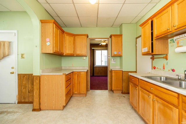 kitchen featuring a paneled ceiling, wood walls, sink, and ceiling fan