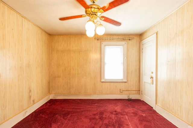 unfurnished room with wood walls, ceiling fan, and carpet floors