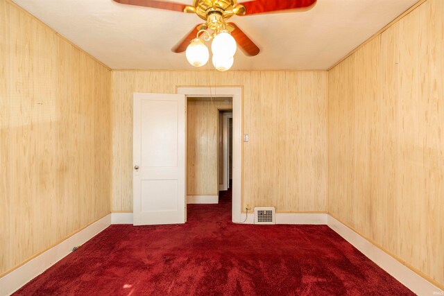 spare room featuring ceiling fan, carpet floors, and wooden walls