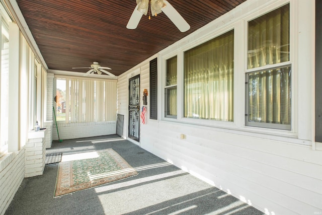 unfurnished sunroom featuring wood ceiling and ceiling fan