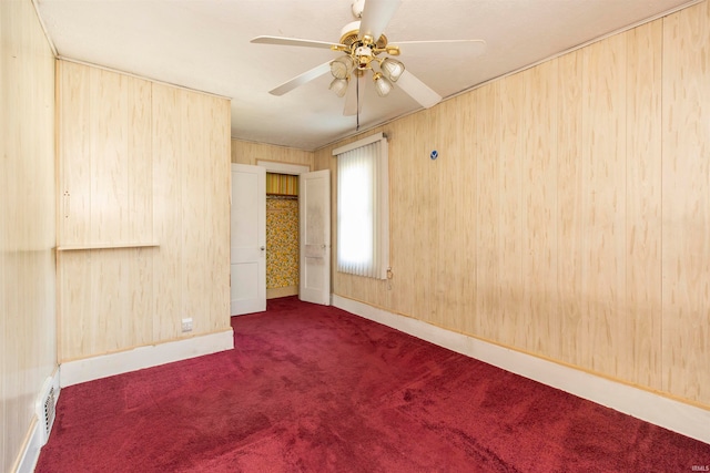 unfurnished bedroom featuring ceiling fan, wooden walls, and dark carpet