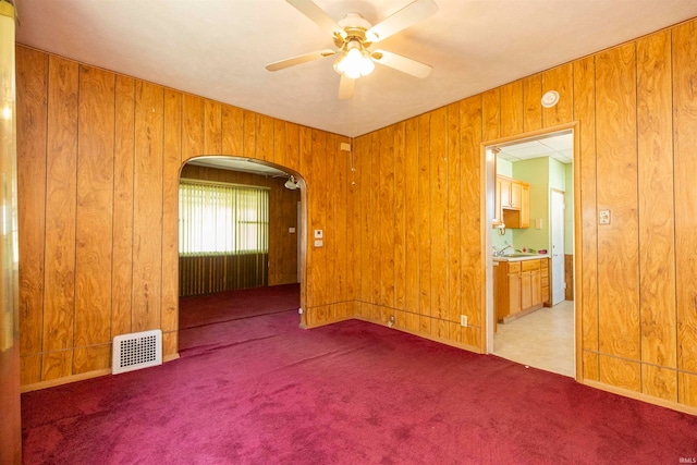 carpeted spare room featuring ceiling fan and wooden walls