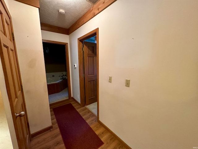 hall with light hardwood / wood-style floors and a textured ceiling