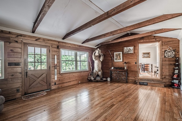 foyer with vaulted ceiling with beams, hardwood / wood-style floors, and wooden walls