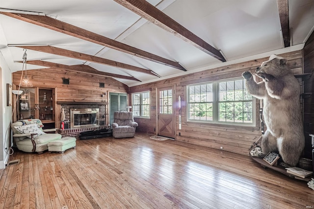 unfurnished living room featuring wooden walls, wood-type flooring, and vaulted ceiling with beams