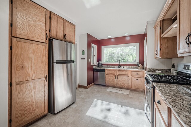 kitchen featuring appliances with stainless steel finishes, light stone counters, sink, and wall chimney range hood