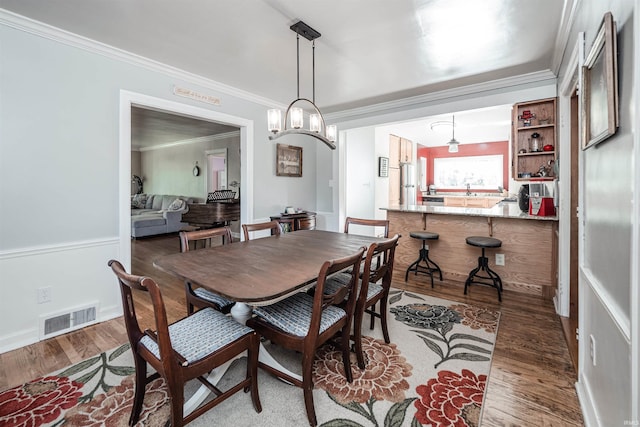 dining space featuring crown molding, dark hardwood / wood-style flooring, and an inviting chandelier