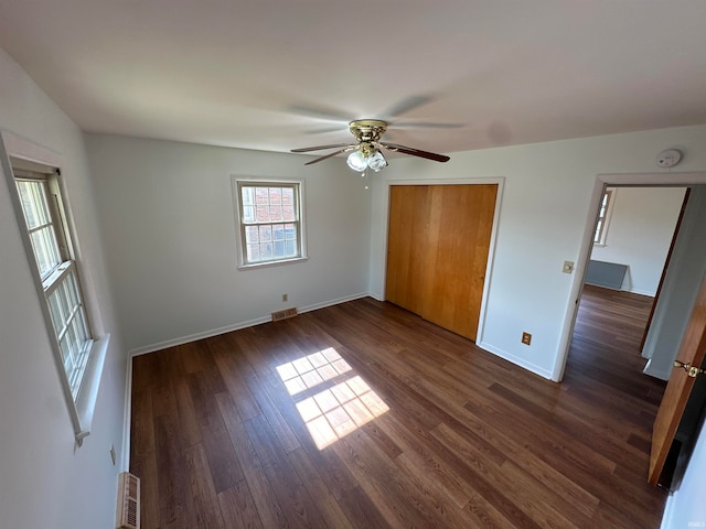 unfurnished bedroom featuring a closet, dark wood-type flooring, and ceiling fan