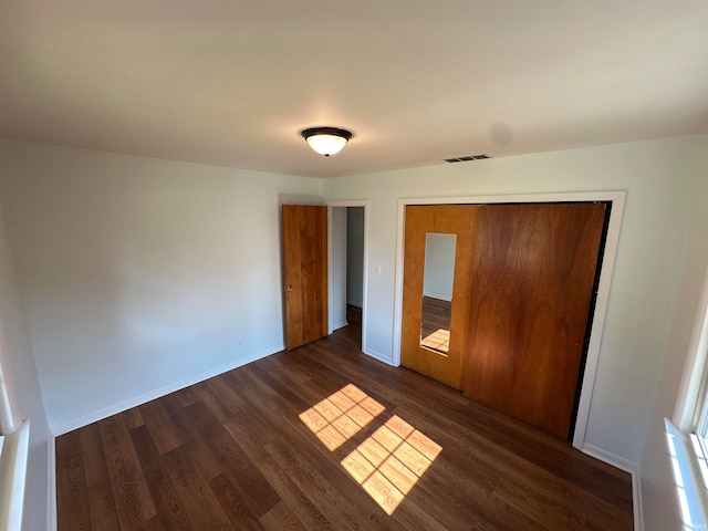 unfurnished bedroom with a closet and dark hardwood / wood-style floors