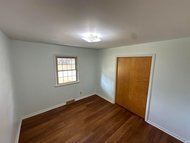 unfurnished bedroom featuring dark wood-type flooring and a closet