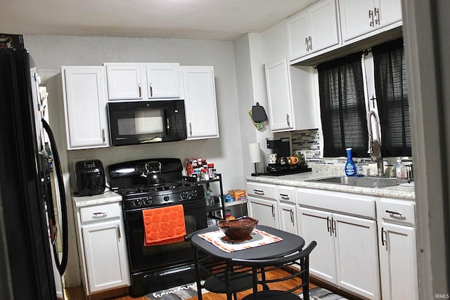 kitchen with tasteful backsplash, black appliances, sink, hardwood / wood-style floors, and white cabinetry