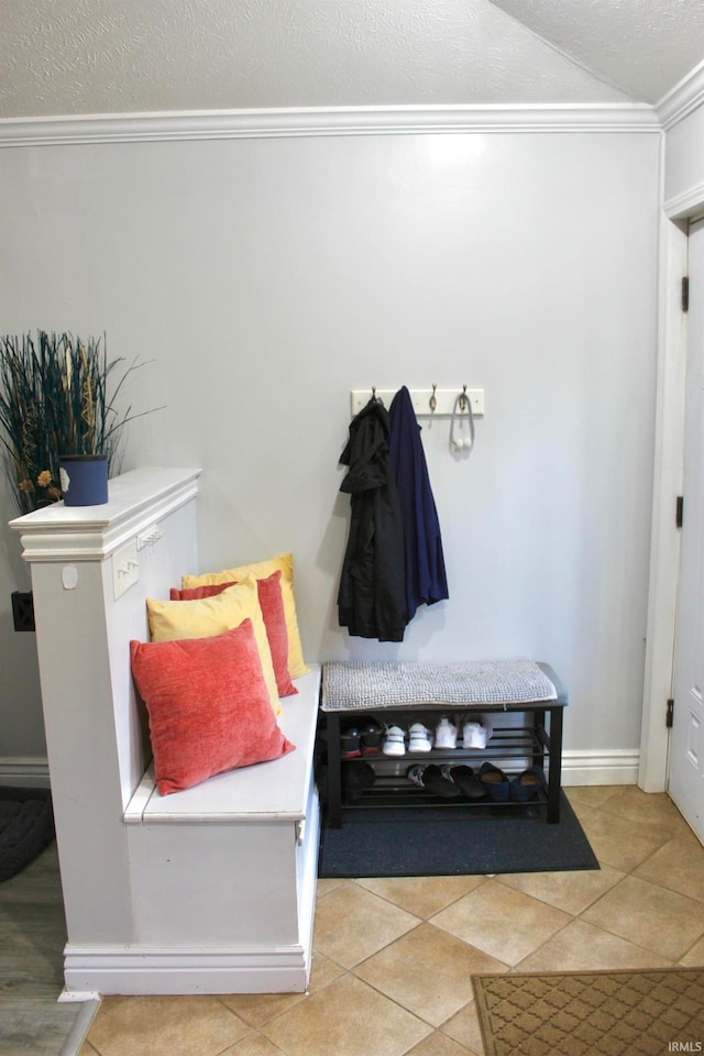 mudroom featuring a textured ceiling, ornamental molding, and light tile patterned floors