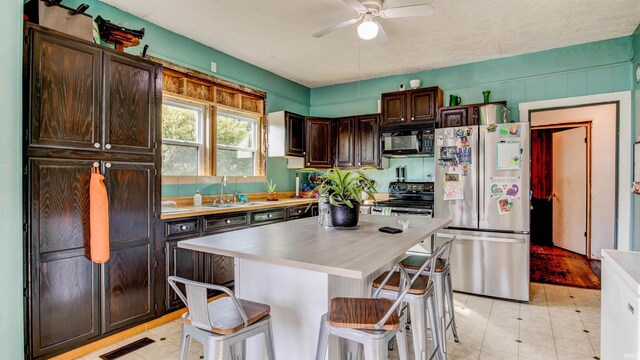 201 S 1st St, Holland, IN 47541 - kitchen featuring black appliances, ceiling fan, dark brown cabinets, a kitchen breakfast bar, and light countertops