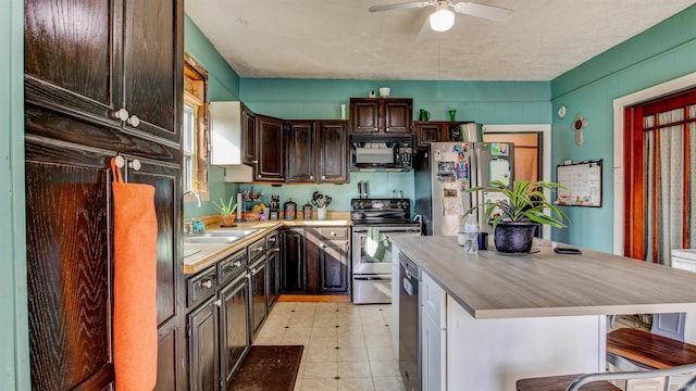 kitchen featuring dark brown cabinets, ceiling fan, appliances with stainless steel finishes, a breakfast bar area, and sink