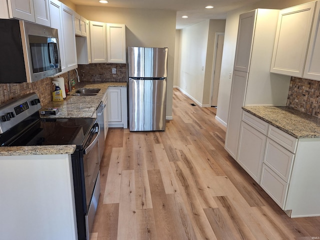 kitchen with decorative backsplash, white cabinets, and stainless steel appliances