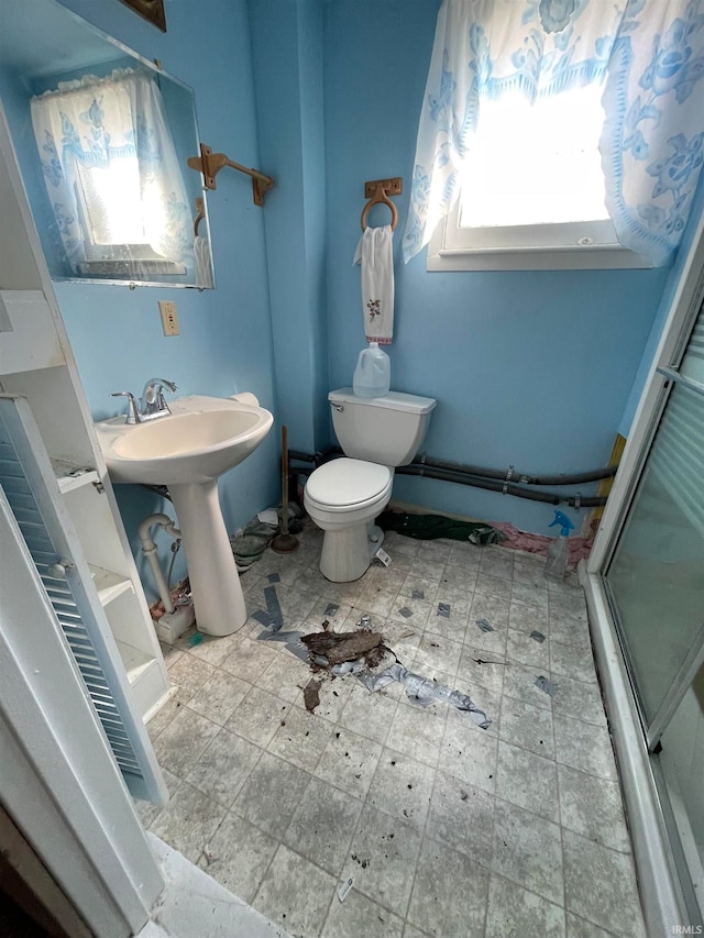 bathroom featuring sink, toilet, and a shower with shower door