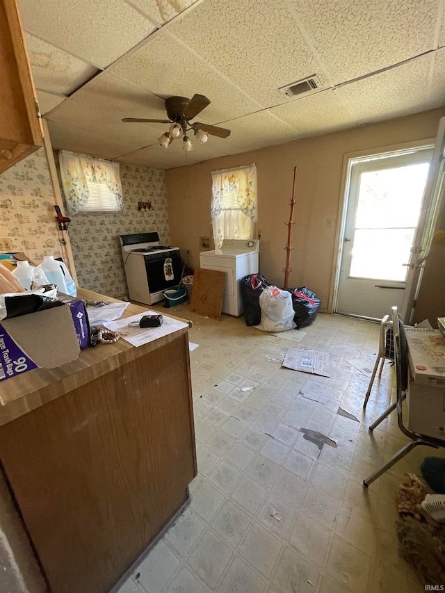 misc room with a drop ceiling, washing machine and clothes dryer, and ceiling fan