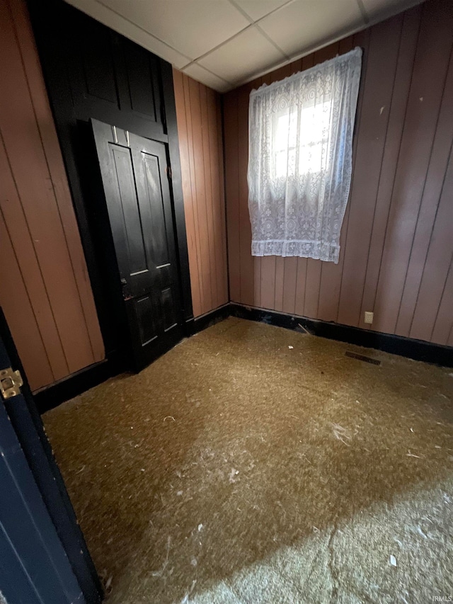 spare room with wooden walls and a paneled ceiling