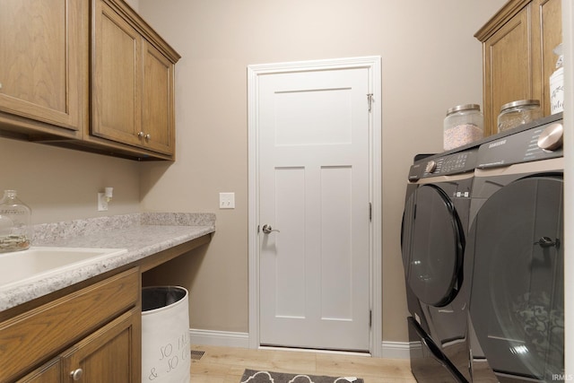 laundry area with light hardwood / wood-style floors and cabinets