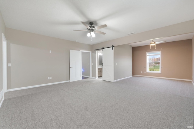 spare room with light carpet, a barn door, and ceiling fan