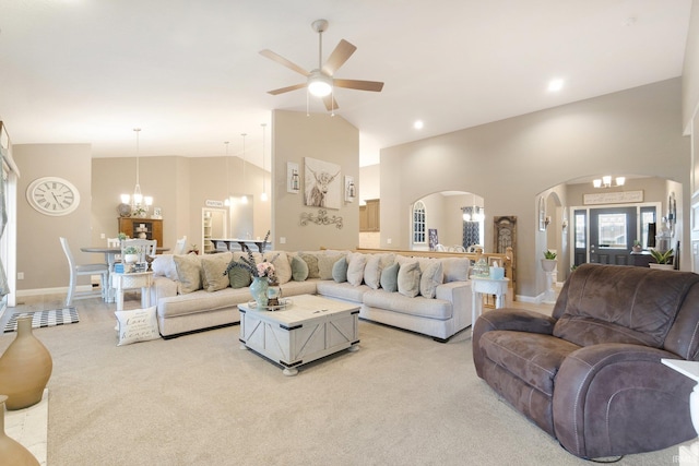 carpeted living room with ceiling fan with notable chandelier and high vaulted ceiling