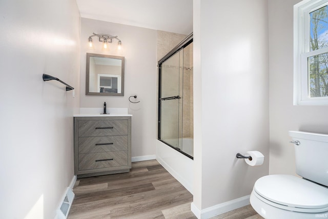 full bathroom with toilet, hardwood / wood-style floors, bath / shower combo with glass door, and vanity