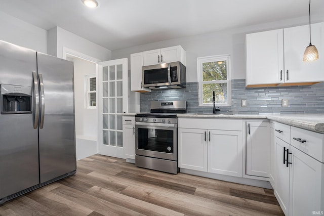 kitchen with light hardwood / wood-style floors, stainless steel appliances, and white cabinets