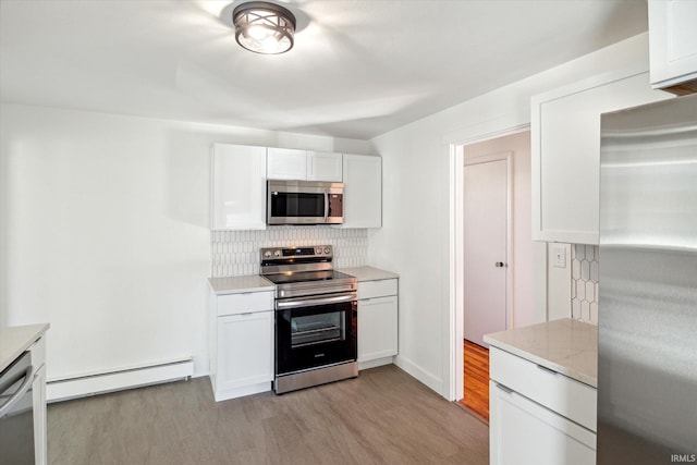 kitchen featuring decorative backsplash, stainless steel appliances, light wood-type flooring, a baseboard radiator, and white cabinets