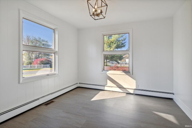 spare room featuring an inviting chandelier, hardwood / wood-style flooring, and a baseboard radiator