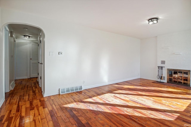 unfurnished living room with hardwood / wood-style flooring and a brick fireplace