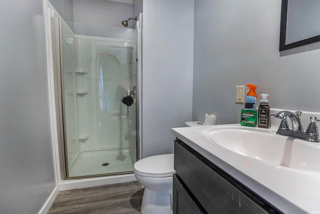 bathroom featuring vanity, hardwood / wood-style floors, a shower with shower door, and toilet