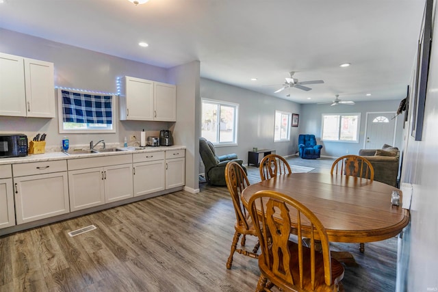 dining area featuring light hardwood / wood-style floors, a healthy amount of sunlight, sink, and ceiling fan