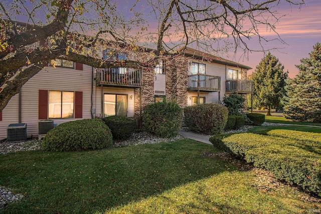 view of front of house featuring a balcony, a yard, and cooling unit