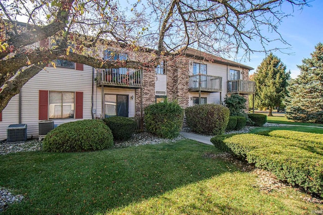 view of front of property featuring a front yard, a balcony, and central AC unit