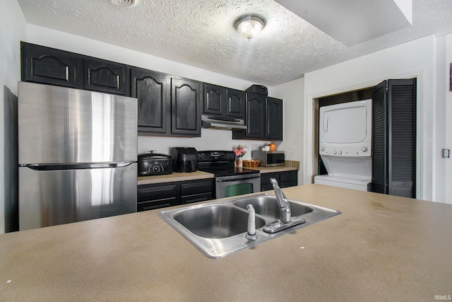 kitchen with sink, stainless steel appliances, a textured ceiling, and stacked washing maching and dryer