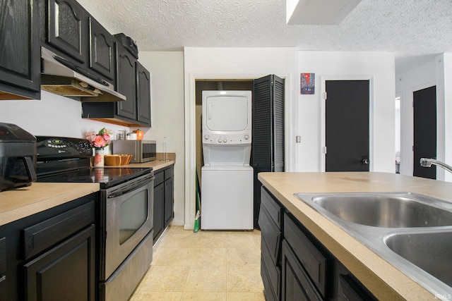 kitchen with appliances with stainless steel finishes, stacked washing maching and dryer, a textured ceiling, and ventilation hood