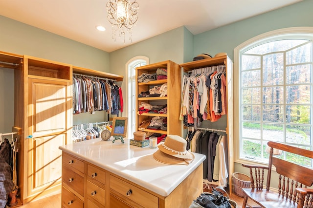 walk in closet featuring light hardwood / wood-style flooring and an inviting chandelier