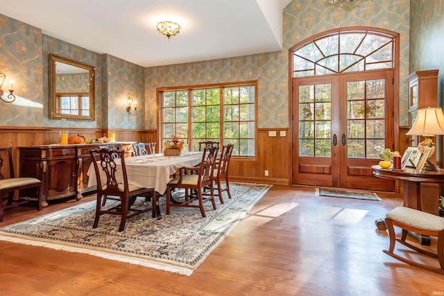 dining room with french doors, wood walls, and light wood-type flooring