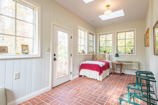 bedroom featuring a skylight, wooden walls, and a wall unit AC