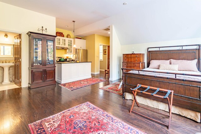 bedroom with connected bathroom, dark hardwood / wood-style flooring, sink, and stainless steel fridge