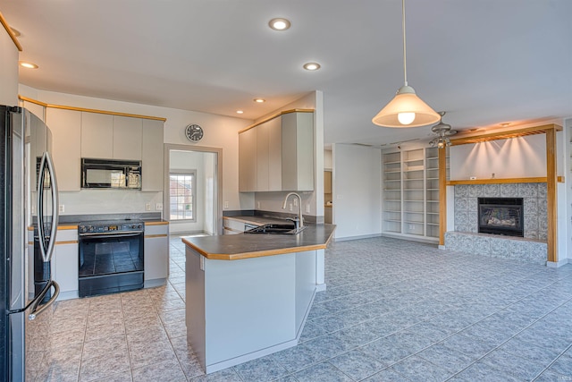 kitchen with black appliances, sink, a fireplace, kitchen peninsula, and pendant lighting